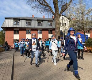 pracownica policji prowadząca grupę maszerujących z kijkami nordic walking