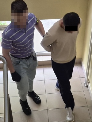 policjant prowadzi mężczyznę w kajdankach