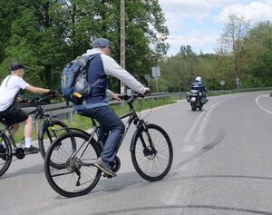 policyjny motocyklista za nim mężczyzna z chłopcem na rowerach