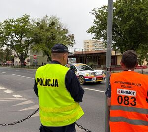 policjant z pracownikiem automobil klub przed nimi na drodze samochód biorący udział w wyścigu