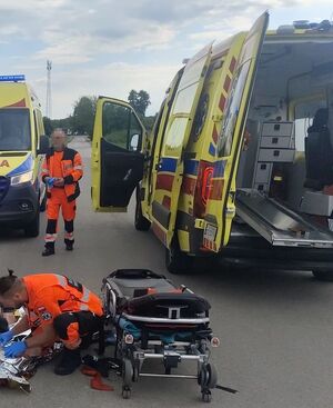 dwie karetki oraz dwóch ratowników przy poszkodowanym nastolatku