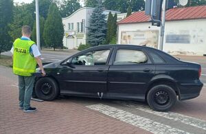 czarny rozbity citroen obok policjant po cywilnemu w kamizelce odblaskowej