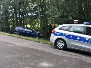 radiowóz a za nim w rowie przy drzewie niebieska toyota