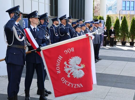 poczet sztandarowy w tle policjanci