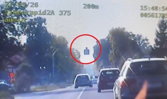 Klatka stop z kamery na pojazd wyprzedzający inne auta przed przejściem dla pieszych.