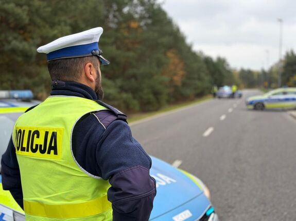 policjant ruchu drogowego patrzący na radiowozy w oddali