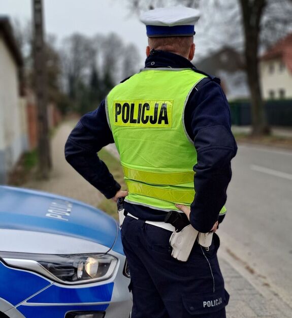 policjant obok radiowozu przy drodze
