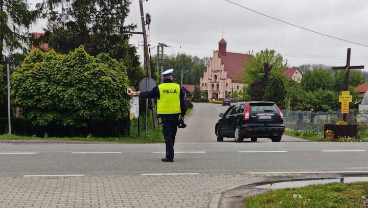 Umundurowany policjant zatrzymuje pojazd do kontroli.