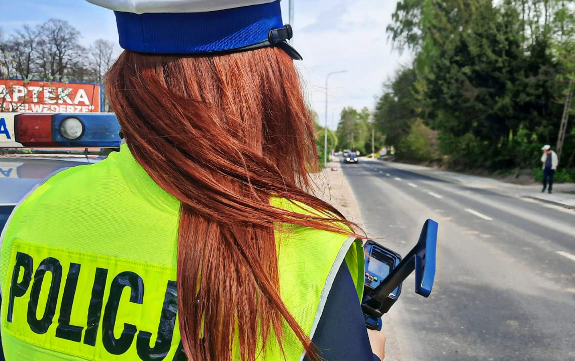 Policjantka umundurowana w czasie służby wukonuje pomiar prędkości.