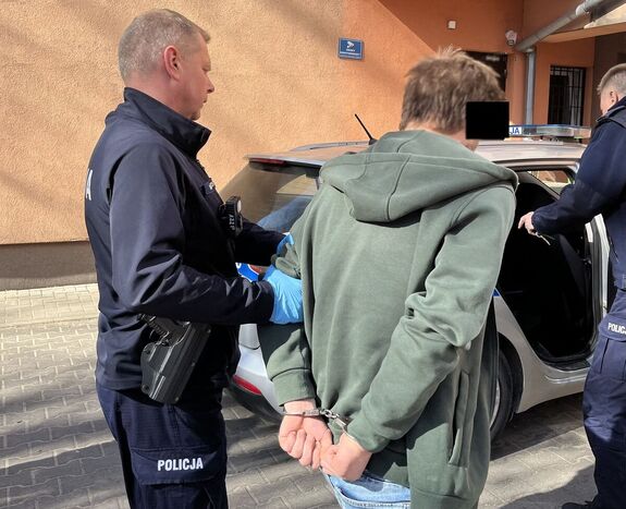 policjant prowadzi do radiowozu zatrzymanego 25-latka
